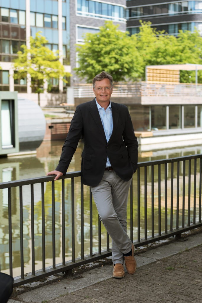Portrait von Björn Behrmann, Vorstand SVG nordwest eG. Er lehnt an einem Geländer vor einem Gewässer.
