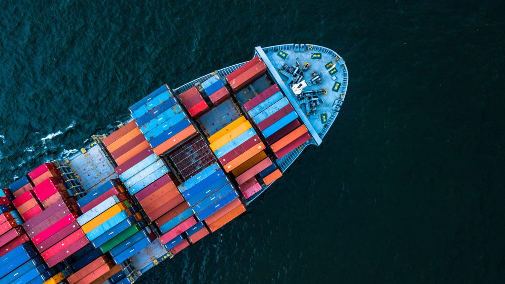 Blick auf ein bunt beladenes Containerschiff auf dem Meer zur Symbolisierung von Factoring im Export.